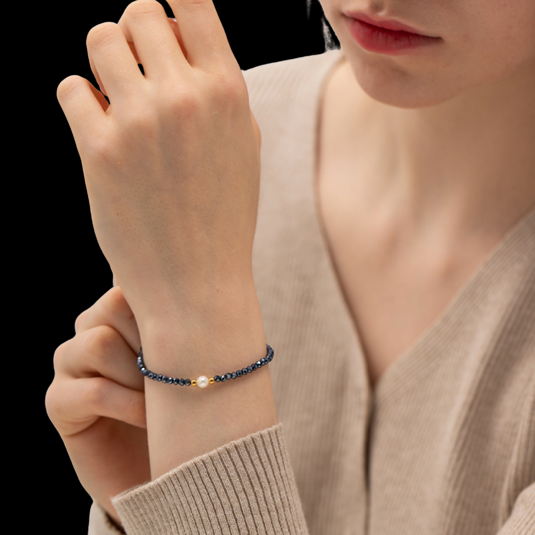 Person wearing a blue beaded bracelet on a plain background