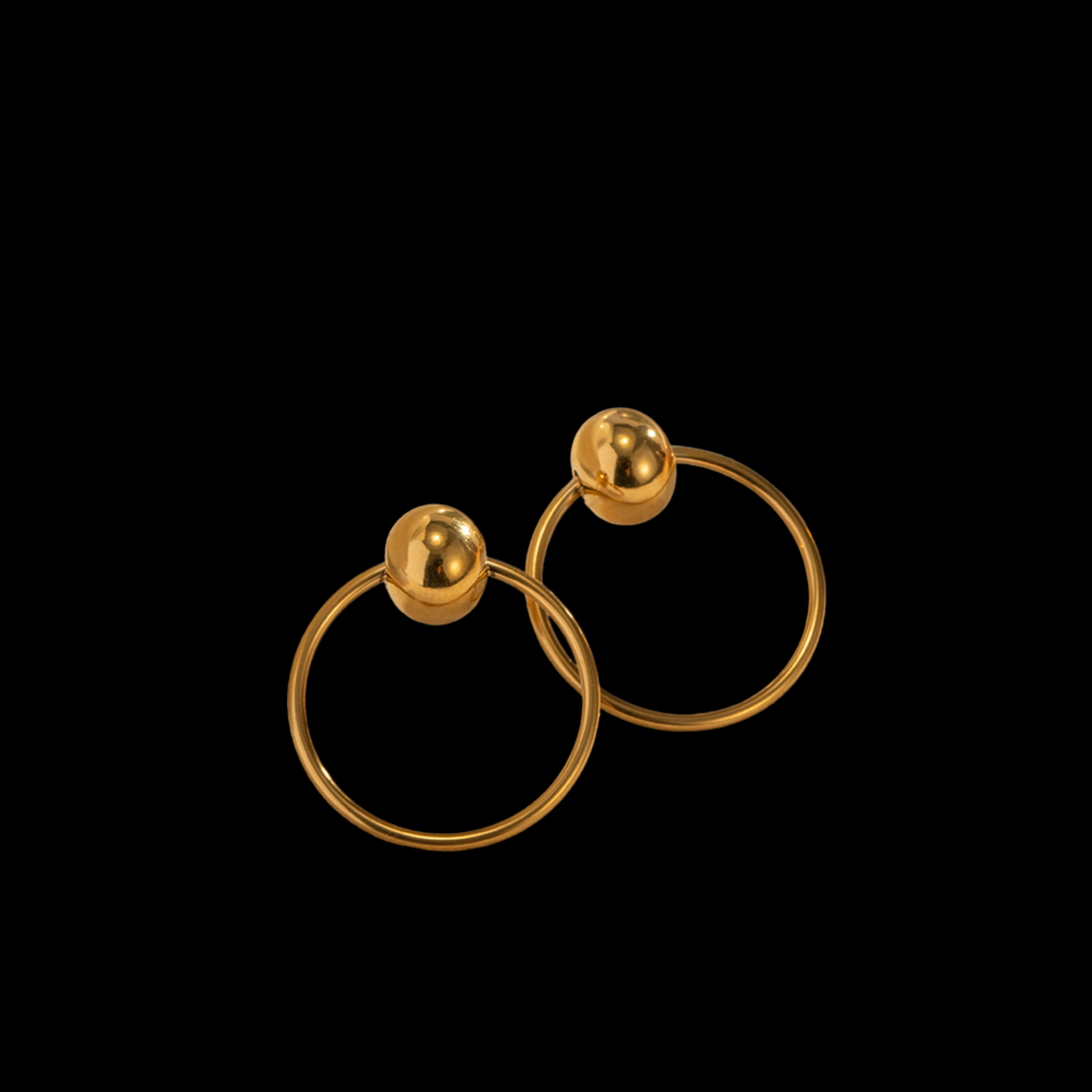 Pair of gold hoop earrings with spherical ends on a black background