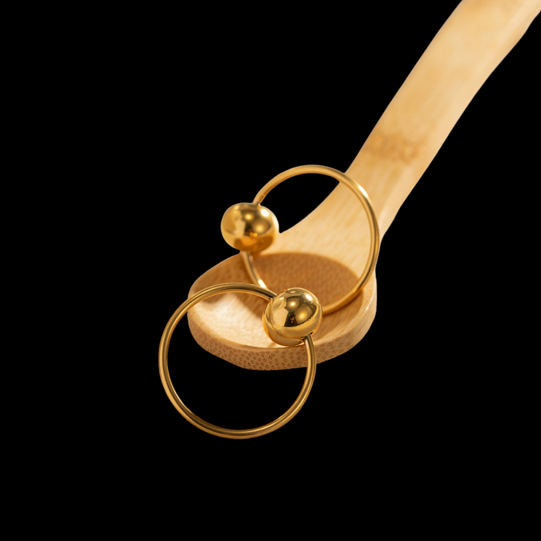 Wooden spoon with gold rings and spherical decorations on a black background